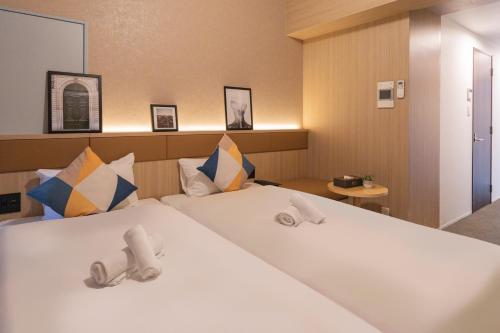 Pokój hotelowy z dużym białym łóżkiem z poduszkami w obiekcie Apartment Hotel 11 Namba Minami w Osace