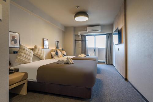 a hotel room with a large bed and a window at Apartment Hotel 11 Namba Minami III in Osaka