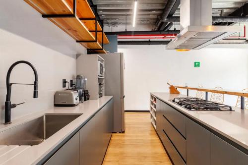 eine Küche mit weißen Arbeitsflächen und Küchengeräten aus Edelstahl in der Unterkunft Mariano Escobedo 48 in Mexiko-Stadt