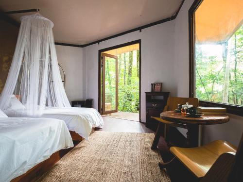 a bedroom with two beds and a table and a window at La Terra Resort in Shiojiri