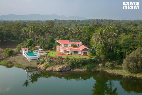 an aerial view of a house on the water at StayVista's Waterway Retreat - Lakeside Oasis with Infinity Pool in Wada