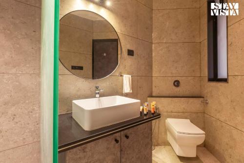 a bathroom with a sink and a toilet and a mirror at StayVista's Waterway Retreat - Lakeside Oasis with Infinity Pool in Wada