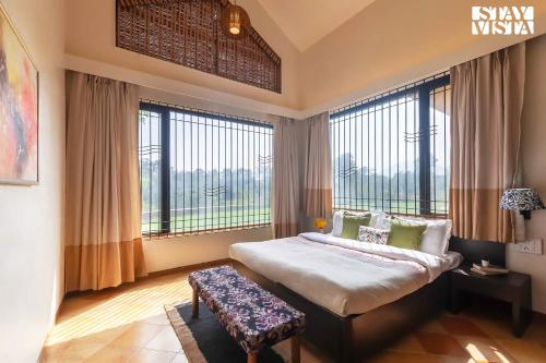 a bedroom with a large bed and large windows at StayVista's Waterway Retreat - Lakeside Oasis with Infinity Pool in Wada