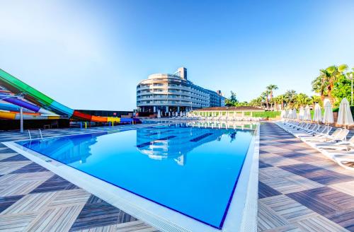 a swimming pool with chairs and a building at Bera Alanya Hotel - Halal All Inclusive in Konaklı