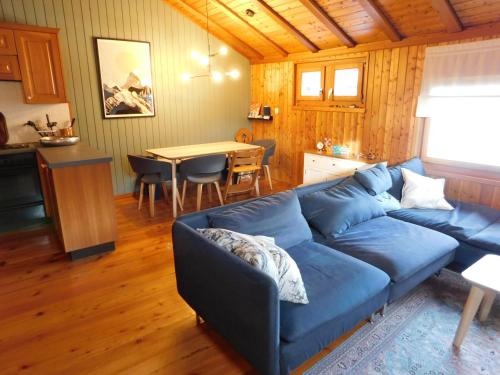 Una sala de estar con un sofá azul y una mesa. en Chalet Bortergade, en Bellwald