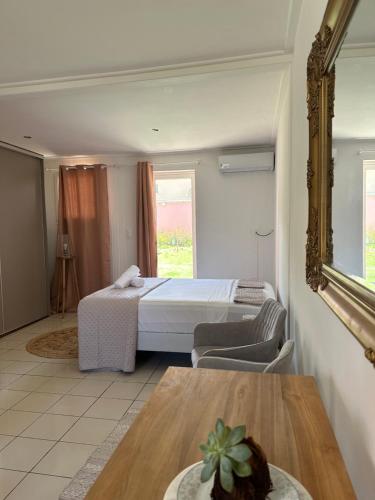 a bedroom with a bed and a table and a mirror at Suite by Villa Serena - Manapany les bains in Saint-Joseph