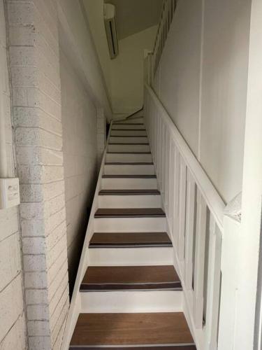 a staircase in a building with white walls and wooden floors at tiny home @ Norwest in Baulkham Hills