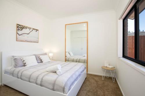 Dormitorio blanco con cama y ventana grande en The Palms Villa - Pet Friendly - 4 Mins to Beach, en Culburra Beach