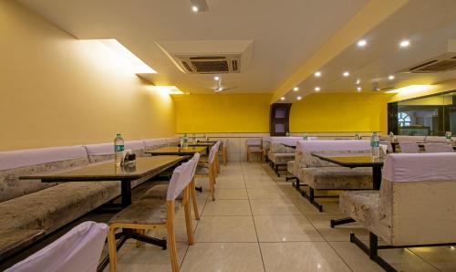 Un restaurante con mesas y sillas y paredes amarillas. en Treebo Suvarna Comforts, en Hassan