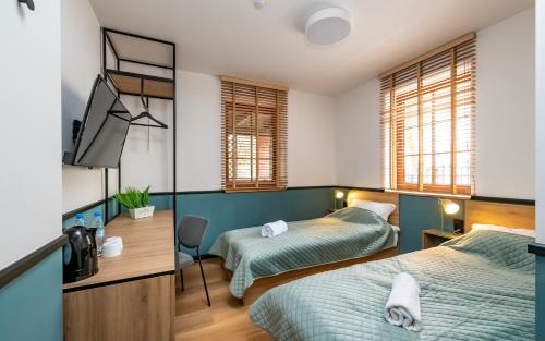 1 dormitorio con 2 camas y escritorio con TV en Noclegi Żelazna 51 en Białystok
