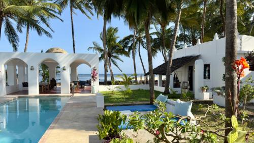 a villa with a swimming pool and palm trees at Sawa Sawa Beach House in Msambweni