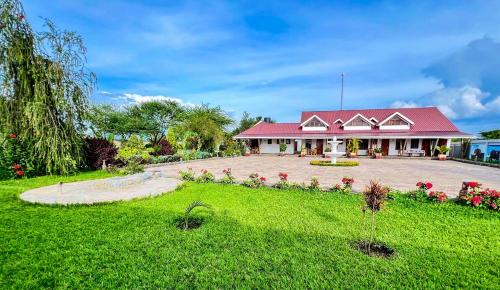 una casa con techo rojo y patio verde en Heart of Africa Lodge en Arusha