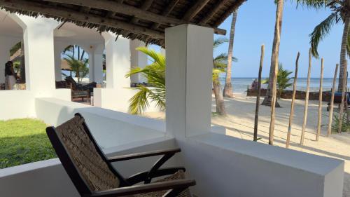 a table and a chair on a porch overlooking the beach at Sawa Sawa Beach House in Msambweni