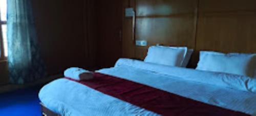um quarto com uma cama grande com lençóis brancos e almofadas em HOTEL TAWANG HOLIDAY Tawang em Tawang