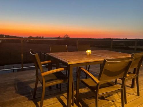 een houten tafel en stoelen op een terras met een zonsondergang bij Spa-Francorchamps / Jahlay Maison 6p de caractère in Jalhay