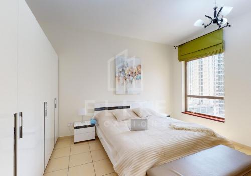 ein weißes Schlafzimmer mit einem Bett und einem Fenster in der Unterkunft Beautiful & Cozy 1BR on JBR Beach! in Dubai