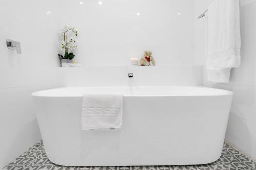 Habitación con baño blanco con bañera blanca. en The Grande Port Stephens Luxurious golf and beach getaway on Horizons Golf Resort en Salamander Bay