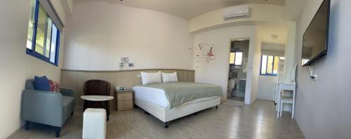 a bedroom with a bed and a chair and a television at Haibian Mingren 50 in Hualien City