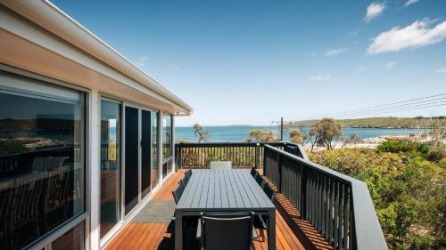 a deck with a table and a view of the ocean at Dolphinview in Coffin Bay