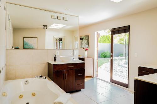 a bathroom with a tub and a sink and a mirror at El Mirador by AvantStay Canyon Views Large Pool Outdoor Grill Games Permit4253 in Palm Springs