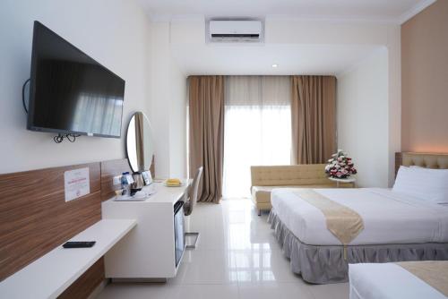 a hotel room with two beds and a flat screen tv at Lorin Syariah Hotel Sentul in Bogor