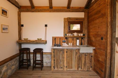 a kitchen with wooden walls and a counter with stools at Rustic Cabin Zlatibor in Ribnica