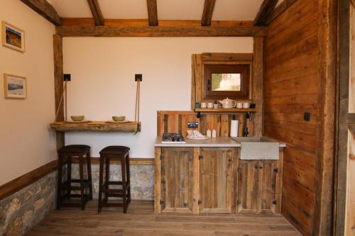 cocina con paredes de madera y encimera con taburetes en Rustic Cabin Zlatibor, en Ribnica