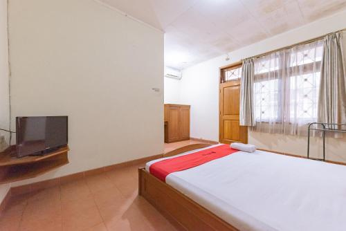 a bedroom with a bed and a flat screen tv at RedDoorz Plus at Wisma Kenanga Sukabumi in Sukabumi