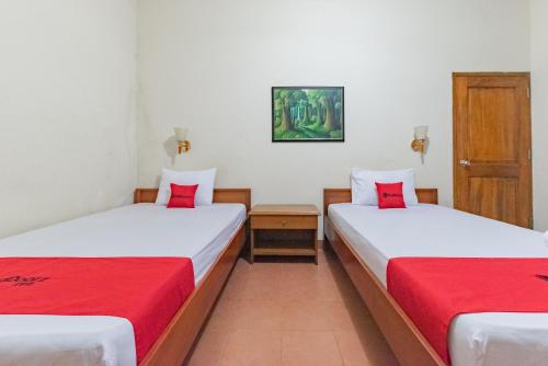 two beds in a room with red pillows at RedDoorz Plus at Wisma Kenanga Sukabumi in Sukabumi