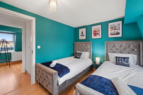 Duas camas num quarto com paredes azuis em Chapel Manor Large 2 Bed Flat Zone 1 em Londres