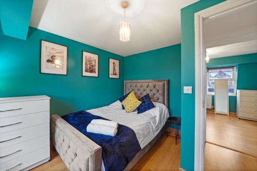 um quarto com paredes verdes e uma cama com uma cómoda branca em Chapel Manor Large 2 Bed Flat Zone 1 em Londres