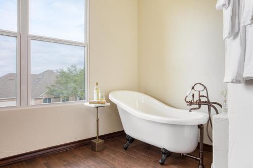 baño con bañera blanca y ventana en Hudson by AvantStay Magnificent Home w Beautiful Views Multiple Living Areas Pool Games en Austin