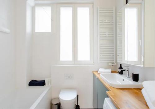 La salle de bains est pourvue d'un lavabo, de toilettes et de 2 fenêtres. dans l'établissement Charmant appartement près du Père Lachaise, à Paris