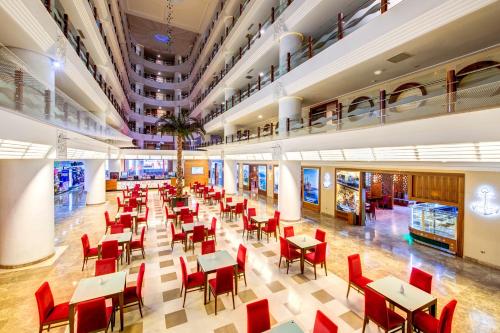 a dining hall with tables and red chairs at Bera Alanya Hotel - Halal All Inclusive in Konaklı