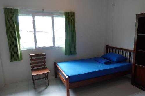 a bedroom with a bed and a chair and a window at Subsavet Village in Baan Tai