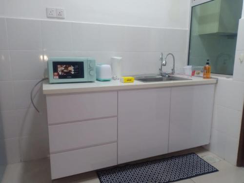 a white kitchen with a sink and a microwave at Homestay Desaru Utama @Escadia in Bandar Penawar