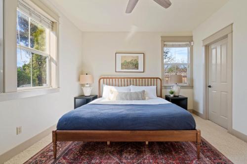 a bedroom with a blue bed and two windows at Fiano by AvantStay Centrally Located Haven w Stunning Courtyard Pool Table in Windsor