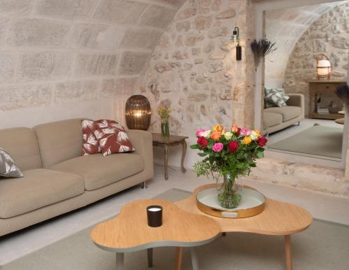 - un salon avec un canapé et une table ornée d'un vase de fleurs dans l'établissement La Maison de Juliette, à Maussane-les-Alpilles