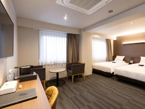 a hotel room with two beds and a desk at Kurayoshi City Hotel in Kurayoshi