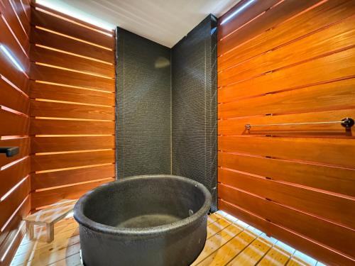 a large bath tub in a room with wooden walls at 温泉付き貸別荘 風車村 E-10 with hot spring in Takashima