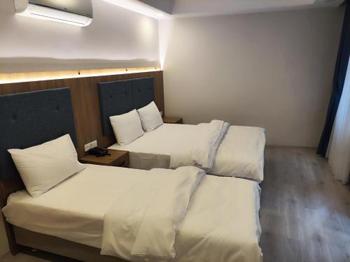 2 camas en una habitación con sábanas y almohadas blancas en Hotel Esve Istanbul en Estambul