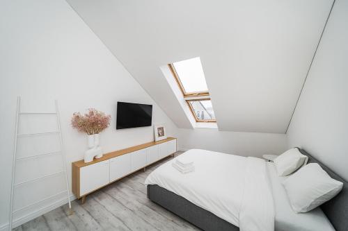 ein weißes Schlafzimmer mit einem Bett und einem TV in der Unterkunft Modern 2-bedroom Apartment in Old Town/URBAN RENT in Kaunas