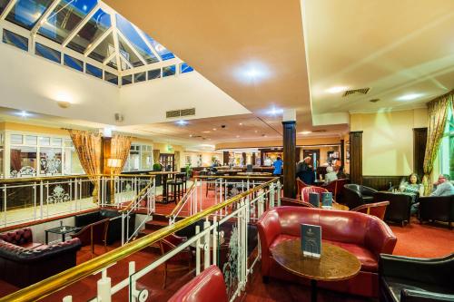 a restaurant with red leather chairs and a bar at Arden Hotel And Leisure Club in Bickenhill