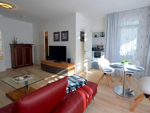 een woonkamer met een rode bank en een tafel bij Villa "Wiederkehr" in Sellin - Wohnung 4 mit Balkon strandnah in Ostseebad Sellin