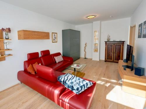 een woonkamer met een rode bank en een tafel bij Villa "Wiederkehr" in Sellin - Wohnung 4 mit Balkon strandnah in Ostseebad Sellin