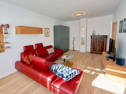 a living room with a red couch and a table at Villa "Wiederkehr" in Sellin - Wohnung 4 mit Balkon strandnah in Ostseebad Sellin