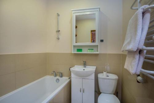 a bathroom with a sink and a toilet and a bath tub at Pensjonat Iskra in Sztum
