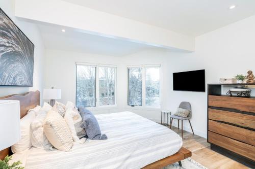 a white bedroom with a bed and a tv at Manitou Riverhouse 115 by AvantStay Spacious Condo in the Centre of Telluride in Telluride
