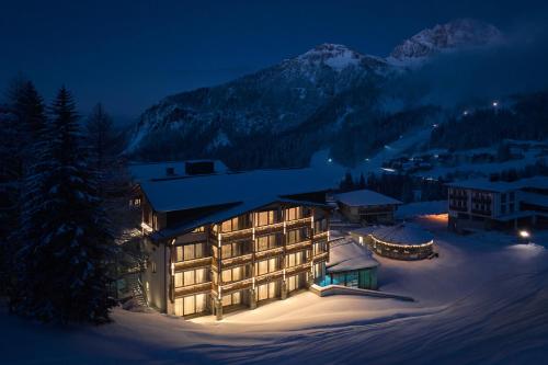 ein großes Gebäude im Schnee in der Nacht in der Unterkunft Hotel Wulfenia 4S - Adults Only in Sonnenalpe Nassfeld