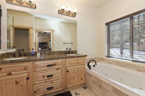 ein Badezimmer mit zwei Waschbecken, einer Badewanne und einem großen Fenster in der Unterkunft Paradise Pines by AvantStay Beautiful Big Bear Home Only 1 Mile To Snow Summit in Big Bear Lake